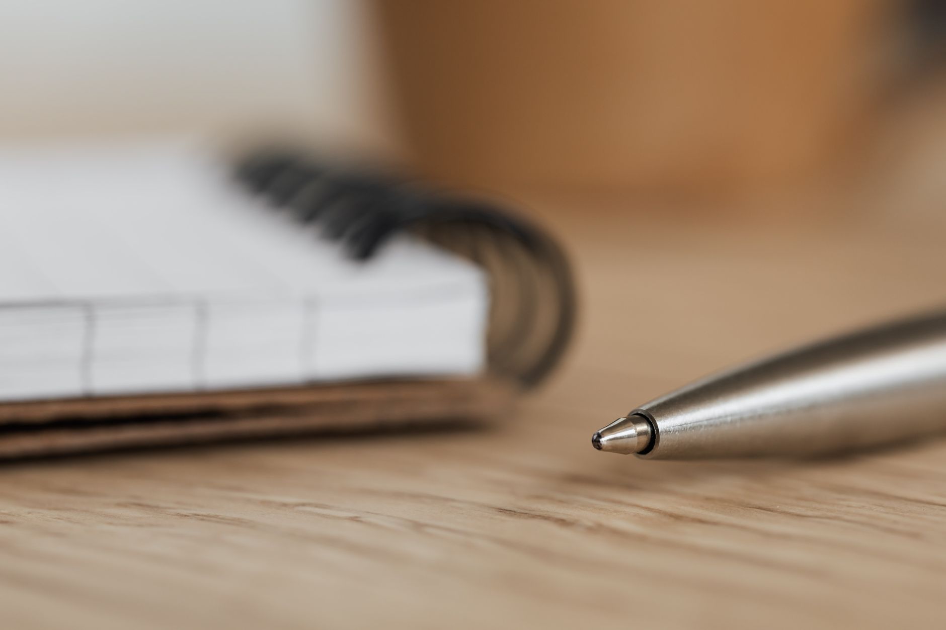 A notebook and pen resting on a wooden desk